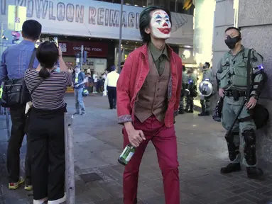 Seorang pria dengan kostum Halloween berjalan melewati petugas polisi di Hong Kong, Kamis (31/10/2019). Para pemrotes Hong Kong menyerukan kepada orang-orang untuk merayakan Halloween dengan mengenakan topeng yang menggambarkan pejabat pemerintah atau tokoh-tokoh menakutkan. (AP Photo/Kin Cheung)