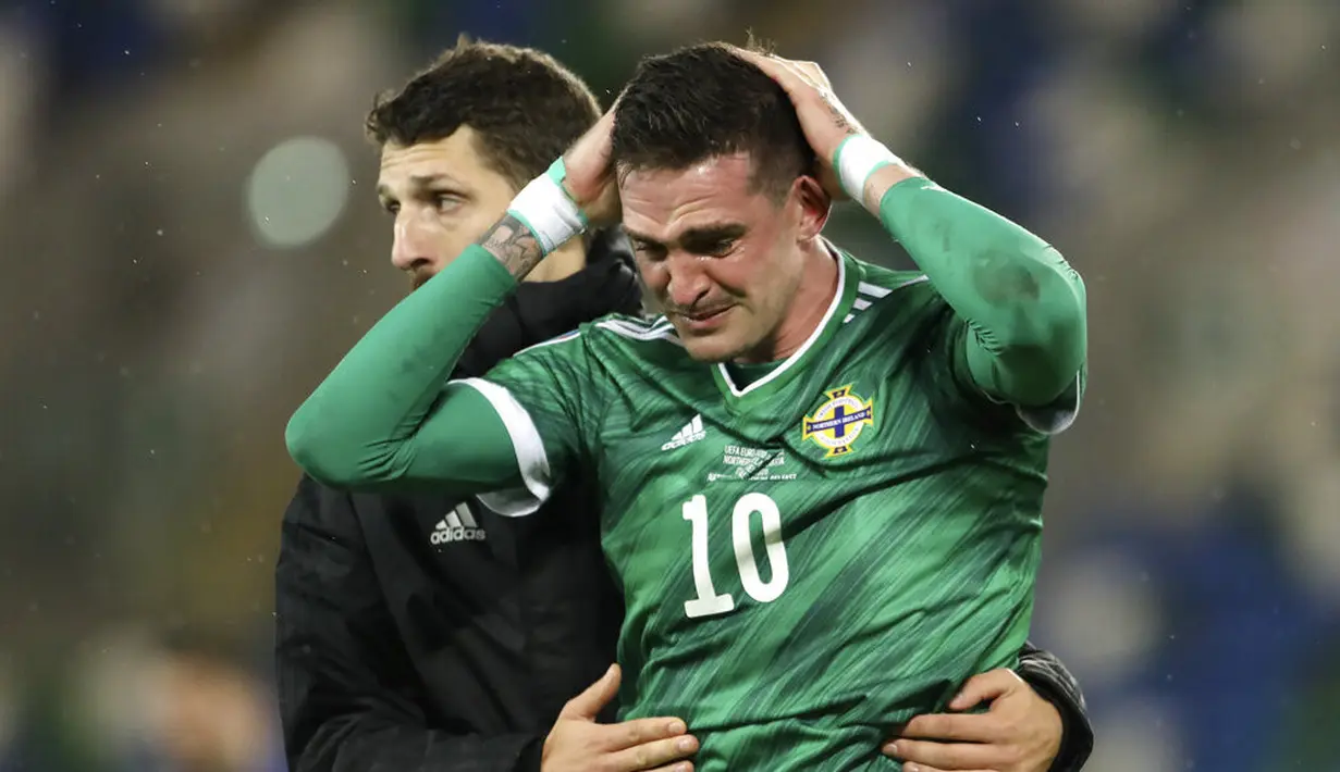 Pemain Irlandia Utara Kyle Lafferty (kanan) dihibur oleh rekan setimnya usai kekalahan mereka dari Slovakia pada pertandingan playoff babak semifinal Euro 2020 di Windsor Park, Belfast, Irlandia Utara, Kamis (12/11/2020). Slovakia lolos ke Euro 2020. (AP Photo/Peter Morrison)