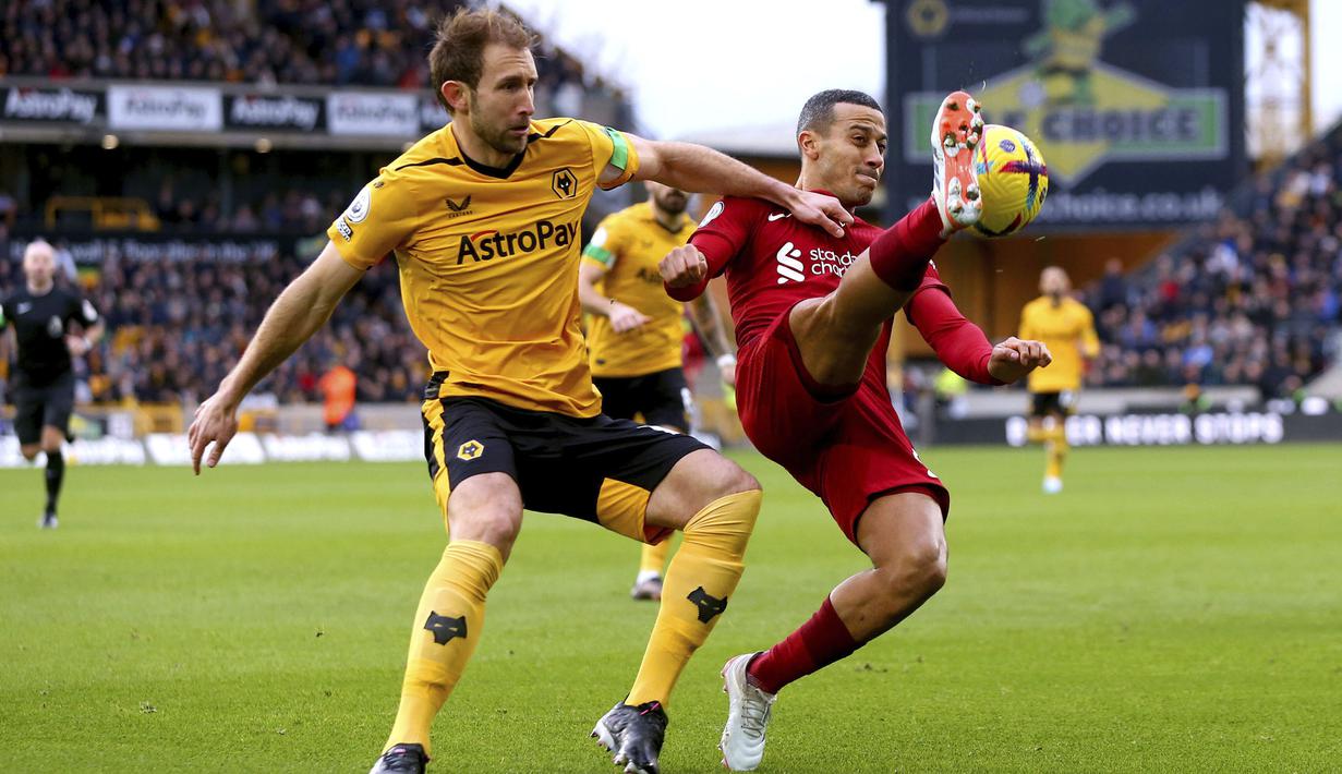 Pemain Liverpool, Thiago Alcantara (kanan) berebut bola dengan pemain Wolverhampton, Craig Dawson pada laga pekan ke-22 Liga Inggris 2022/2023 di Molineux Stadium, Sabtu (04/02/2023). Liverpool kalah dengan skor 0-3 dari Wolves. (AP via PA/Tim Goode)