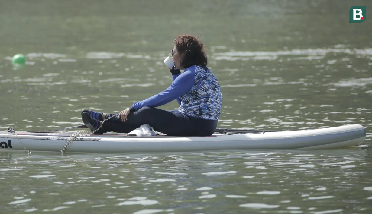 Menteri Kelautan dan Perikanan, Susi Pudjiastuti, minum kopi saat bermain paddle board di Danau Sunter, Jakarta, Minggu (25/2/2018). Kegiatan ini dilakukan dalam rangka Festival Danau Sunter. (Bola.com/Okie Prabhowo)