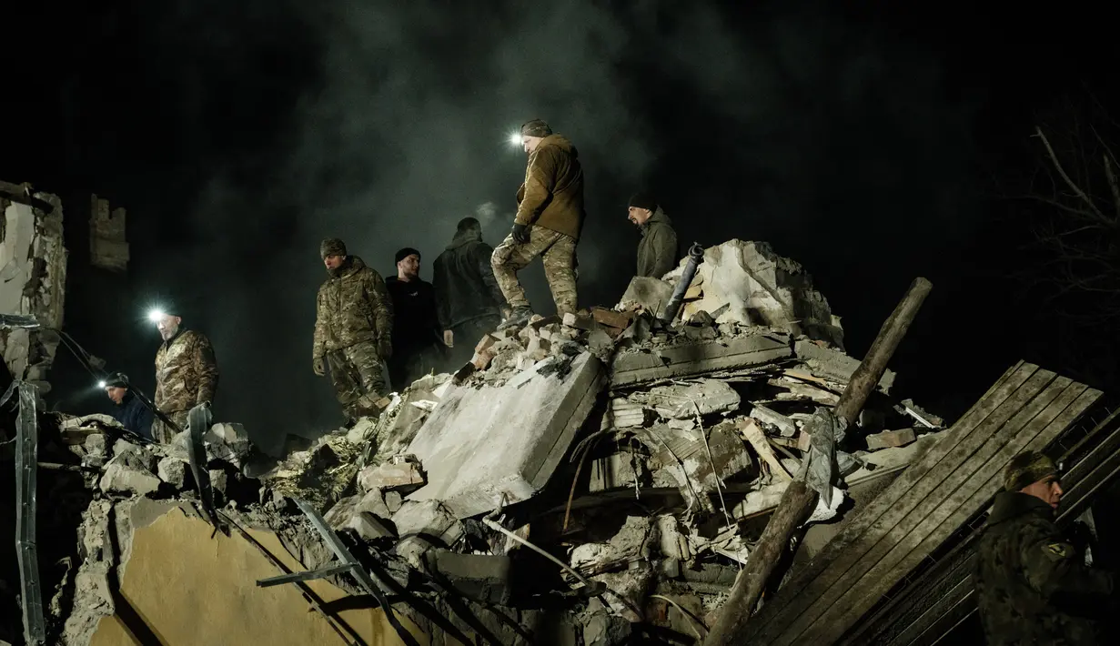 <p>Tim penyelamat memindahkan puing-puing untuk mencari korban selamat di gedung apartemen yang hancur terkena roket pada malam hari di pusat kota Kramatorsk, Ukraina timur, pada Rabu (1/2/2023). Seperti dilansir AFP, serangan rudal Rusia itu dilaporkan terjadi pada Rabu malam, sekitar pukul 21.45 waktu setempat. (Yasuyoshi CHIBA / AFP)</p>