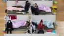 Aktivitas pasien dengan gejala ringan virus corona COVID-19 yang beristirahat pada malam hari di stadion olahraga yang diubah menjadi rumah sakit darurat di Wuhan, China pada 18 Februari 2020. Jumlah korban virus corona hingga Kamis (20/2) kembali meningkat menjadi 2.120 orang. (STR/AFP)