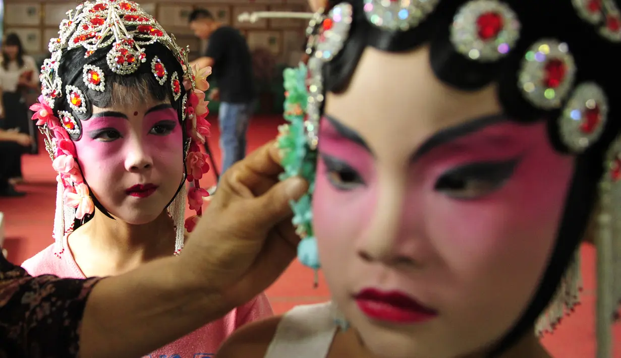 Anak-anak memakai riasan wajah sebelum menampilkan Opera Hahaqiang di Mumendian, Qingxian, Provinsi Hebei, China, 27 Agustus 2020. Opera Hahaqiang terdaftar sebagai warisan budaya tak benda nasional China pada 2006. (Xinhua/Mu Yu)