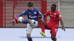 Pemain Union Berlin, Anthony Ujah, berebut bola dengan pemain Schalke, Juan Miranda, pada laga Bundesliga di Weserstadion Minggu (7/6/2020). Kedua tim bermain imbang 1-1. (AP/Michael Sohn)