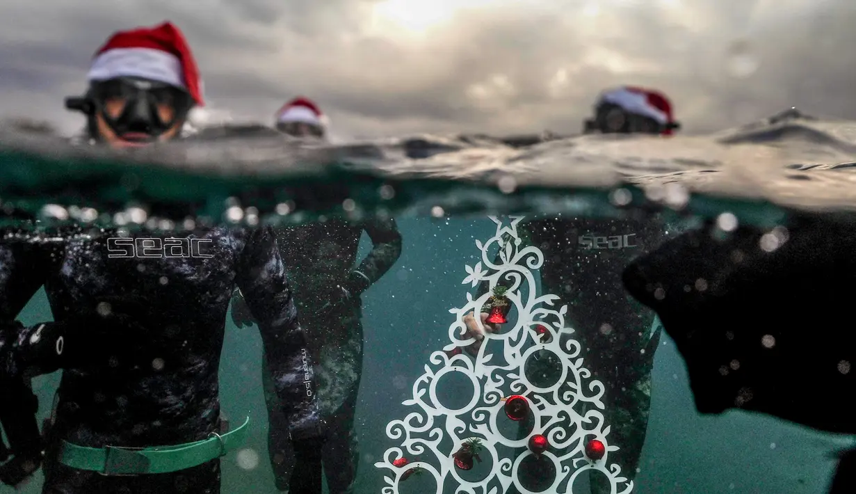 Penyelam berpose saat akan menempatkan pohon Natal di dasar laut lepas pantai Tripoli, Lebanon, Selasa (18/12). Hal ini dilakukan untuk menyambut Natal. (IBRAHIM CHALHOUB/AFP)