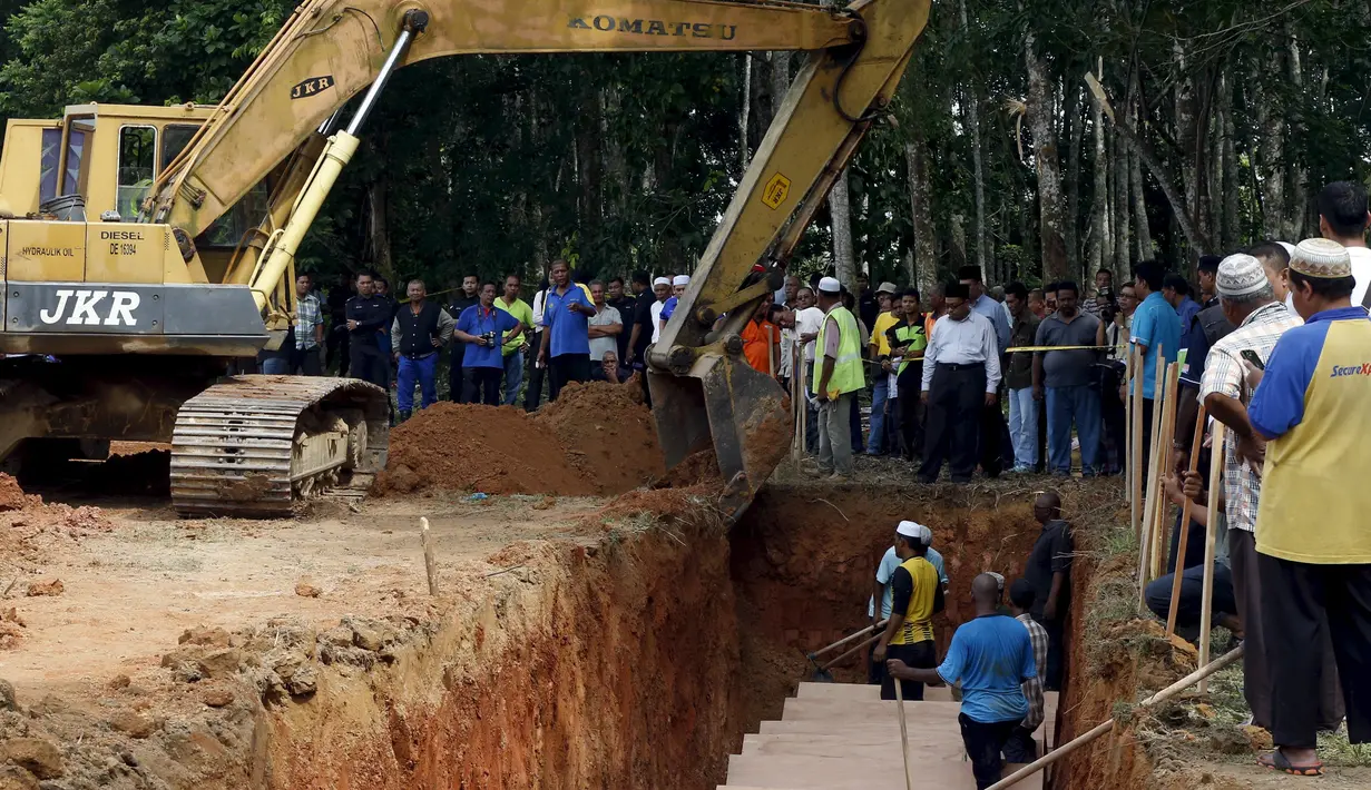 Alat berat disiagakan di sekitar lokasi pemakaman massal jenazah yang di duga etnis Rohingya di Alor Setar, Malaysia, Senin (22/6/2015).  21 dari 106 jenazah tak dikenal yang ditemukan bulan lalu dimakamkan hari ini. (Reuters/Olivia Harris)