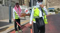 Dua petugas haji dari Indonesia tengah bersiap membantu para jemaah menyeberangi jalan. Mereka rela berjam-jam berada di bawah terik cuaca panas Kota Makkah, Arab Saudi untuk memastikan para jemaah menyeberang dengan selamat. (Foto: Kemenag)