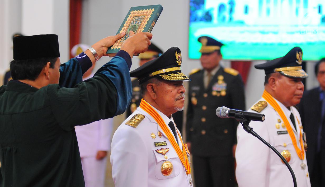 Gubernur dan Wakil Gubernur terpilih Maluku Utara Abdul Gani Kasuba (kiri) dan Al Yasin disumpah dengan kitab suci Alquran saat pelantikan di Istana Negara, Jakarta, Jumat (10/5/2019). Mahkamah Konstitusi (MK) memutuskan keduanya sebagai pemenang Pilgub Malut 2018. (Liputan6.com/Angga Yuniar)