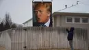 Seorang warga saat mengabadikan baliho besar calon Presiden AS Donald Trump dengan ponselnya di halaman belakang rumah George Davey di West Des Moines, Iowa, (25/1/2016). (AFP/JIM WATSON)