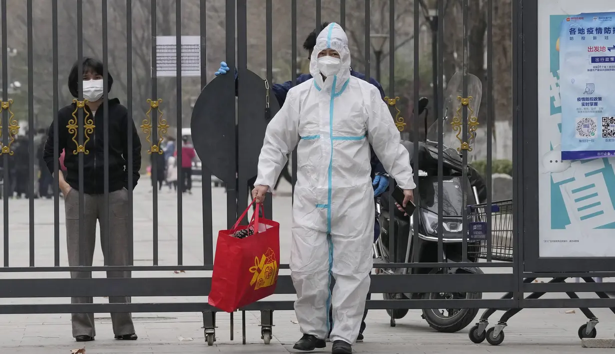Pekerja dengan APD membantu menyerahkan tas dari penduduk di dalam komunitas yang lockdown di Beijing, Minggu (13/3/2022). Pihak berwenang menangguhkan layanan bus ke Shanghai setelah jumlah kasus baru covid-19 di timur laut China meningkat tiga kali lipat pada hari Minggu. (AP Photo/Ng Han Guan)