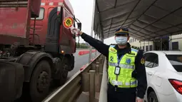 Seorang staf memandu sejumlah kendaraan untuk berhenti di tepi jalan guna mengukur suhu tubuh para pengemudinya di dekat sebuah gerbang tol sebagai upaya memerangi wabah di Nanning, Daerah Otonom Etnis Zhuang Guangxi, China selatan, pada 1 Februari 2020. (Xinhua/Lu Boan)