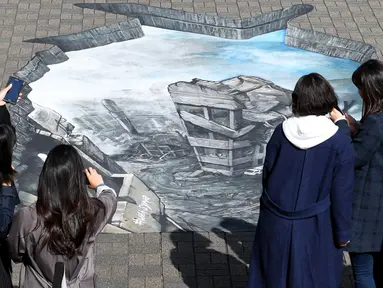 Sejumlah warga melihat sebuah karya ilusi optik 3-D yang bergambar kota Aleppo yang hancur akibat perang di kampus Universitas Meiji di Tokyo, Jepang (18/11). Karya ini ditampilkan untuk menimbulkan rasa kemanusiaan di Jepang. (AFP/Toshifumi Kitamura)