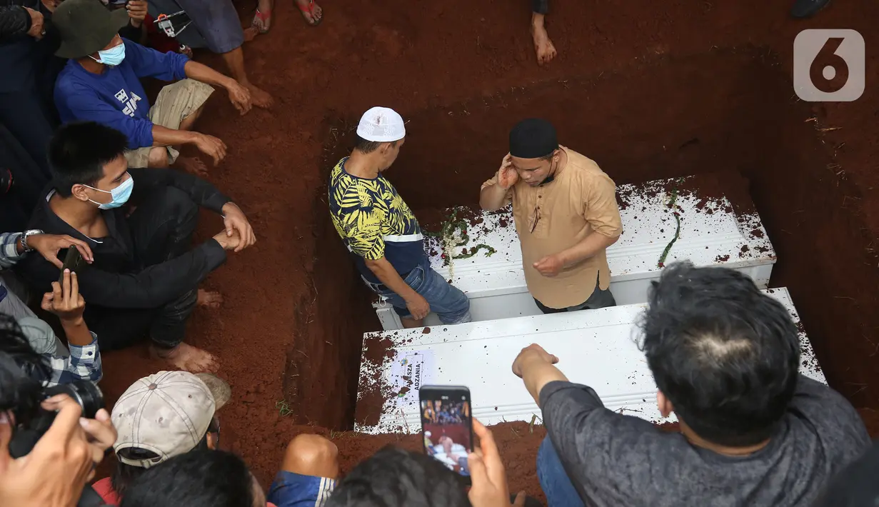 Seorang pria melakukan azan saat pemakaman Vanessa Angel dan Bibi Andriansya di Taman Makam Islami Malaka, Pesanggrahan, Jakarta, Jumat (5/11/2021). Vanessa Angel dan Bibi Andriansyah meninggal dalam kecelakaan lalu lintas di Tol Mojokerto-Jombang pada 4 November 2021. (Liputan6.com/Herman Zakharia)