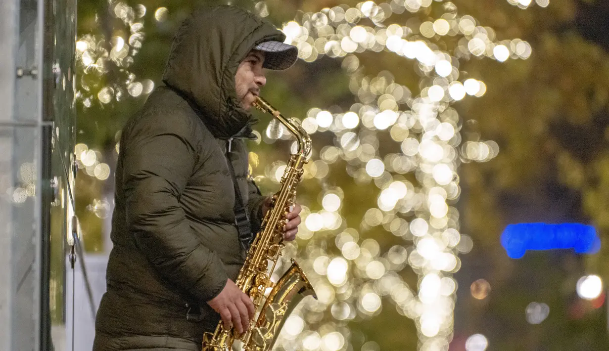 Seorang pria memainkan saksofonnya di pasar Natal di depan balai kota Wina di Wina, Austria (19/11/2019). Christkindlmarkt atau Pasar Natal bertebaran di Kota Vienna. Setiap distrik, ataupun spot-spot wisata memiliki Pasar Natal masing-masing. (AFP Photo/Joe Klamar)