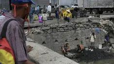 Pria mencari potongan tembaga, emas atau perak untuk dijual di tengah pandemi virus corona baru di Sungai Guaire yang tercemar, di lingkungan Quinta Crespo di Caracas, Venezuela (19/1/2021). Krisis ekonomi Venezuela telah mengirim jutaan orang melarikan diri. (AP Photo/Matias Delacroix)