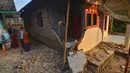 Warga berbincang dekat rumah yang rusak usai gempa melanda Pandeglang, Banten, Sabtu (3/8/2019). Sekitar 500 warga Kecamatan Sumur, Ujung Kulon, Kabupaten Pandeglang, masih mengungsi di Hunain Sementara (Huntara) akibat gempa Banten. (RONALD SIAGIAN/AFP)