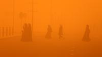 Pejalan kaki menyeberang jalan di tengah badai debu parah di Kuwait City pada 23 Mei 2022. Badai pasir telah melanda Timur Tengah dalam beberapa hari terakhir, dan menjadi fenomena yang para ahli peringatkan dapat berkembang luas karena perubahan iklim. (Yasser Al-Zayyat / AFP)