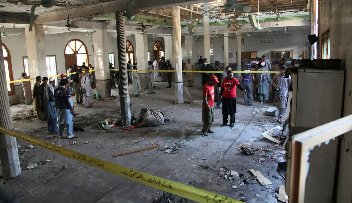 Petugas penyelamat dan aparat kepolisian memeriksa lokasi ledakan bom di sebuah madrasah di kota Peshawar, Pakistan, Selasa (27/10/2020). Ledakan di salah satu sekolah agama tersebut menewaskan sedikitnya tujuh orang, termasuk anak-anak, dan melukai puluhan lainnya. (AP Photo/Muhammad Sajjad)