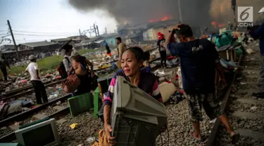 Seorang ibu menyelamatkan sebuah televisi saat kebakaran ratusan rumah bedeng di permukiman liar belakang Hotel Alexis, Pademangan, Jakarta, Sabtu (16/9). Untuk memadamkan api, sebanyak 20 unit pemadam kebakaran dikerahkan. (Liputan6.com/Faizal Fanani)