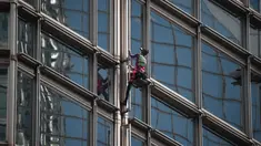 Alain Robert yang dijuluki 'French Spiderman' memanjat gedung pencakar langit Cheung Kong Center di Hong Kong, Jumat (16/8/2019). Pria berusia 57 tahun tersebut memanjat Cheung Kong Center dalam kondisi panas dan lembab pada Jumat pagi. (Lillian SUWANRUMPHA/AFP)