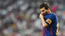 Striker Barcelona, Lionel Messi, meluapkan kekecewaanya dengan menggigit baju usai takluk dari Real Madrid pada laga Piala Super Spanyol 2017 di Stadion Santiago Bernabeu, Rabu (16/8/2017). Real Madrid menang 2-0 atas Barcelona. (AFP/Gabriel Bouys)