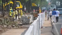 Sejumlah warga melintas disebelah proyek pembangunan pedestrian di Jalan Lapangan Banteng, Jakarta, Minggu (16/7). Pembangunan pedestrian ini bagian dari upaya meningkatkan fasilitas penunjang pejalan kaki di Ibu Kota. (Liputan6.com/Helmi Afandi)