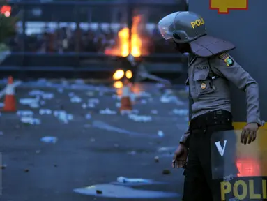 Seorang petugas mengamati aksi mahasiswa memperingati Hari Sumpah Pemuda di depan Gedung DPR, Senayan, Jakarta, Rabu (28/10/2015). Dalam aksinya para mahasiswa membakar ban. (Liputan6.com/Johan Tallo) 