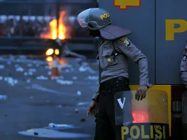 Seorang petugas mengamati aksi mahasiswa memperingati Hari Sumpah Pemuda di depan Gedung DPR, Senayan, Jakarta, Rabu (28/10/2015). Dalam aksinya para mahasiswa membakar ban. (Liputan6.com/Johan Tallo) 