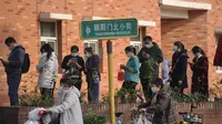 Pengendara skuter melewati warga yang antre untuk menerima suntikan booster di tempat vaksinasi di Beijing, Senin (25/10/2021). Sebuah provinsi di China barat laut yang sangat bergantung pada pariwisata menutup semua lokasi wisata pada Senin setelah menemukan kasus baru COVID-19 (AP Photo/Andy Wong)
