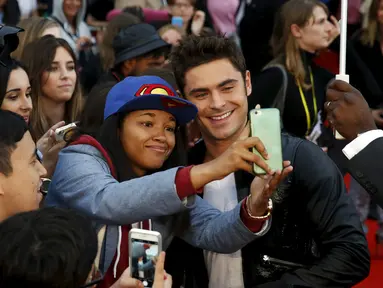 Aktor Zac Efron (kanan) berfoto selfie dengan para penggemarnya saat menghadiri pemutaran perdana film 'We Are Your Friends' di Brixton Oval, London, Inggris. Selasa (11/8/2015). (REUTERS/Luke MacGregor)