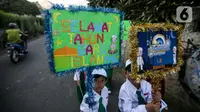 Dengan berseragam lengkap, anak-anak berjalan di sisi jalan dengan membawa poster bertuliskan ucapan "Selamat Tahun Baru Islam. (Liputan6.com/Faizal Fanani)