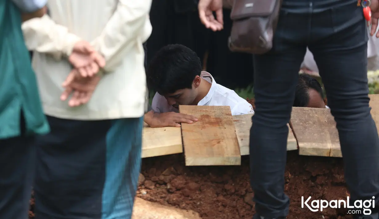 Tidak hanya menyaksikan prosesi pemakaman, Maxime juga turun langsung ke liang lahat. Sebelum turun, sang kekasih yang setia mendampingi menawarkan diri untuk menyimpan ponsel dan sepatunya. [KapanLagi.com/Budy Santoso]