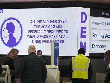 Peringatan elektronik menyarankan para pelancong tentang persyaratan untuk mengenakan masker di konter check-in United Airlines di terminal Bandara Internasional Denver di Denver (26/12/2021). Maskapai menunda ratusan penerbangan pada hari Minggu (26/12). (AP Photo/David Zalubowski)
