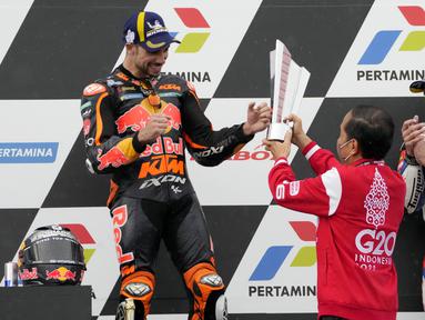Presiden RI, Joko Widodo menyerahkan langsung trofi kepada pembalap KTM, Miguel Oliveira, yang naik podium MotoGP Mandalika di Sirkuit Mandalika, Lombok, Minggu (20/03/2022). (AP Photo/Achmad Ibrahim)