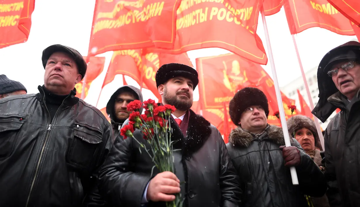 Sejumlah orang membawa bendera dan bunga saat menghadiri upacara memperingati 65 tahun kematian Joseph Stalin di Lapangan Merah, Moskow (5/3). (AFP/Kirill Kudryavtsev)