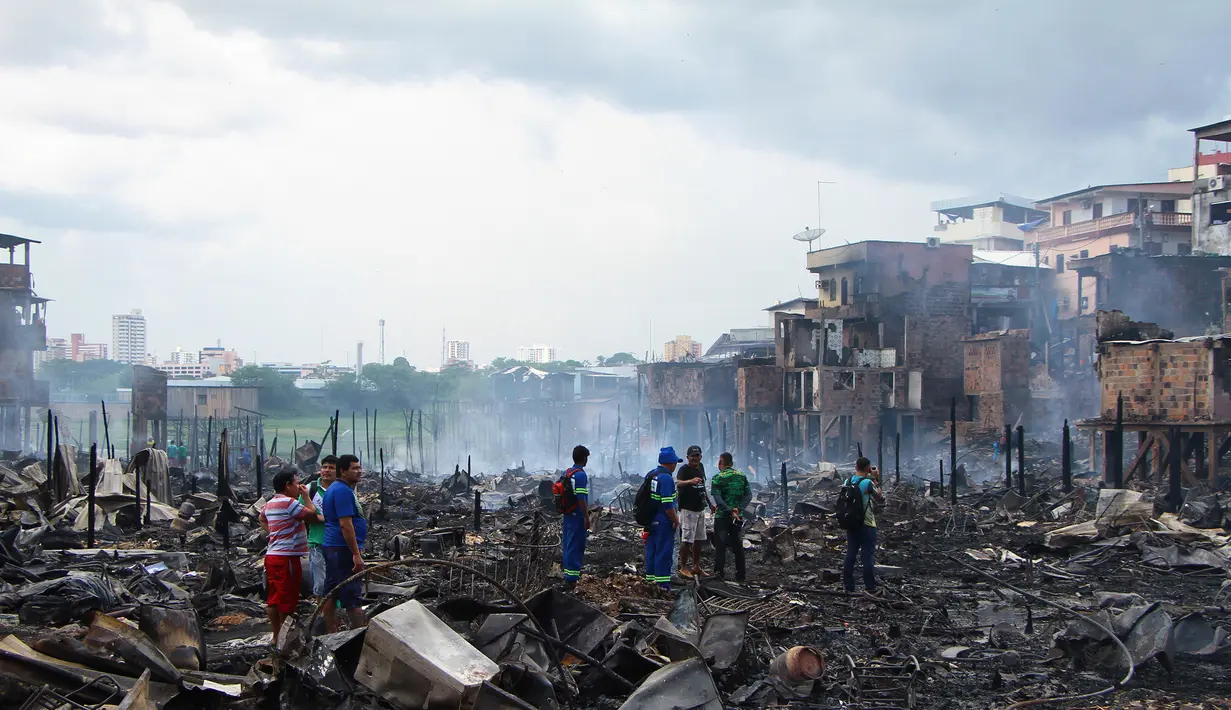 Sejumlah warga melihat sisa-sisa rumah yang hangus di lingkungan Educandos di Manaus, Brasil (17/12). Para pihak berwenang mengatakan setidaknya 600 rumah kayu hanggus terbakar. (AP Photo/Edmar Barros)