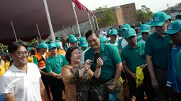 Menteri Koordinator Bidang Kemaritiman Luhut Binsar Panjaitan berfoto bersama seorang warga saat menggelar gerakan aksi bersih di kawasan pesisir Cilincing, Jakarta Utara, Sabtu (6/4). (Liputan6.com/Immanuel Antonius)