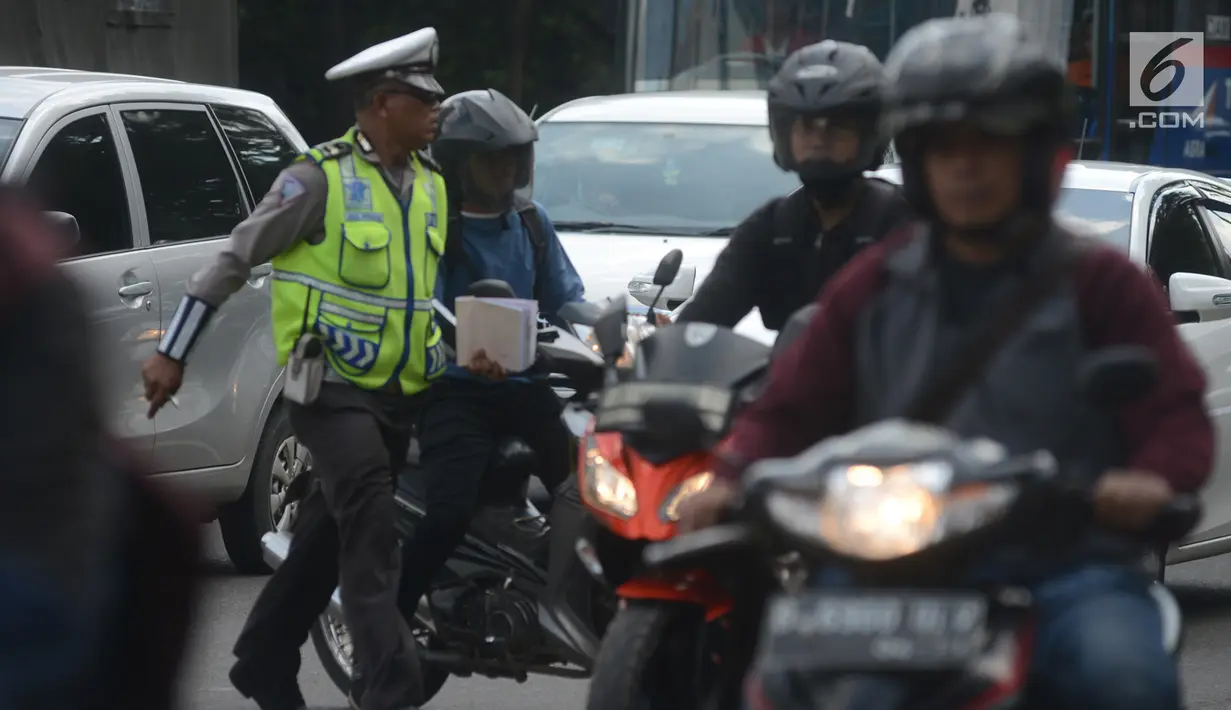 Polantas memberhentikan pengendara motor saat Operasi Patuh Jaya 2018 di Jalan DI Panjaitan, Jakarta Timur, Jumat (27/4). Khusus untuk razia ini, para polantas akan memburu mereka yang menggunakan ponsel sambil berkendara. (Merdeka.com/Imam Buhori)