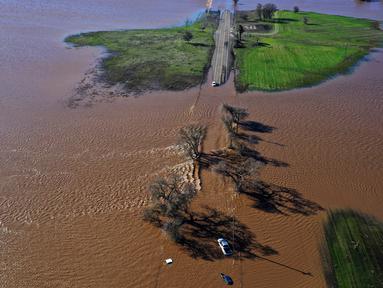 Tiga kendaraan terendam banjir setelah hujan lebat pada Malam Tahun Baru yang menyebabkan tanggul jebol di Dillard Road, Wilton, California, Amerika Serikat, 1 Januari 2023. Badai dahsyat yang menerjang California menyebabkan banjir, pohon tumbang, hingga tanah longsor. (Hector Amezcua/The Sacramento Bee via AP)
