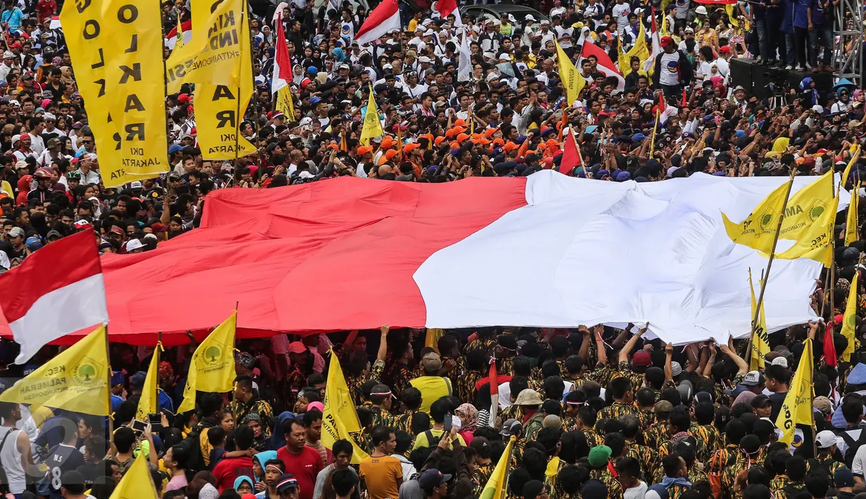 Bendera Merah Putih raksasa dibentangkan oleh para peserta parade 'Aksi Kita Indonesia' di Bundaran HI, Jakarta, Minggu (4/12). Nyanyian berbagai lagu nasional pun berkumandang saat para peserta parade memutari Bundaran HI. (Liputan6.com/Fery Pradolo)