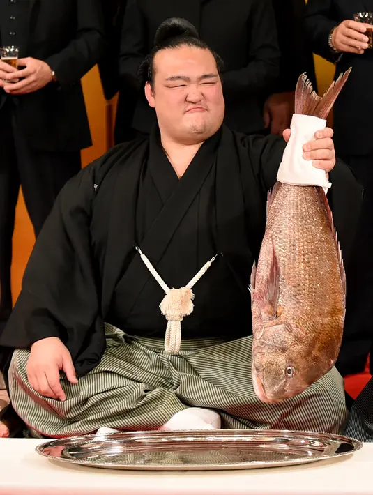 Ekspresi Kisenosato Yutaka saat mendapat hidangan ikan red sea bream dalam upacara yang berlangsung di Tokyo, Jepang, Rabu (25/1). (AFP Photo/Toru Yamanaka) 