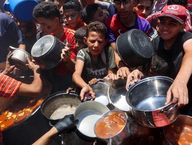 Warga Palestina berusaha mendapatkan makanan di dapur umum yang menyediakan makanan hangat di lingkungan Rimal, kota Gaza pada 18 Juni 2025. (Omar AL-QATTAA/AFP)