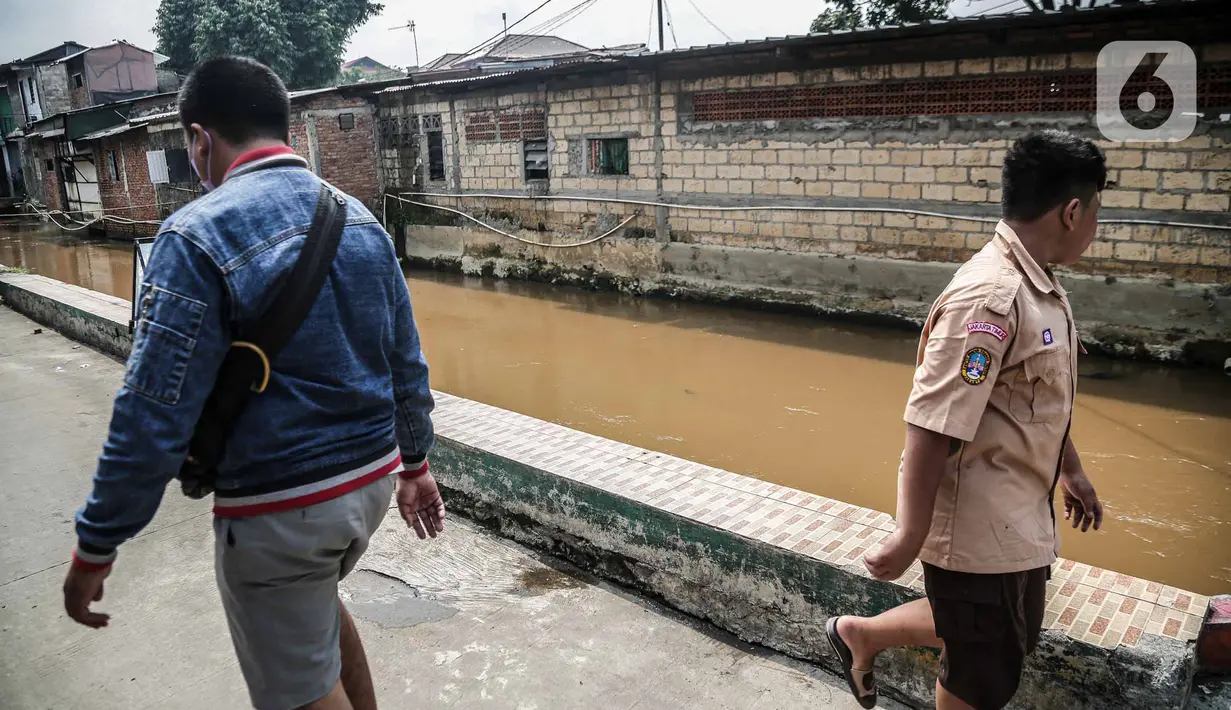 Pejalan kaki melintas di bantaran Kali Induk Kramat Jati, Jakarta, Rabu(18/5/2022). Pemprov DKI Jakarta melalui Dinas Sumber Daya Air (SDA) berencana akan menormalisasi Kali Induk secara keseluruhan guna mencegah banjir yang melanda kawasan tersebut saat hujan deras mengguyur. (Liputan6.com/FaizaL Fanani)