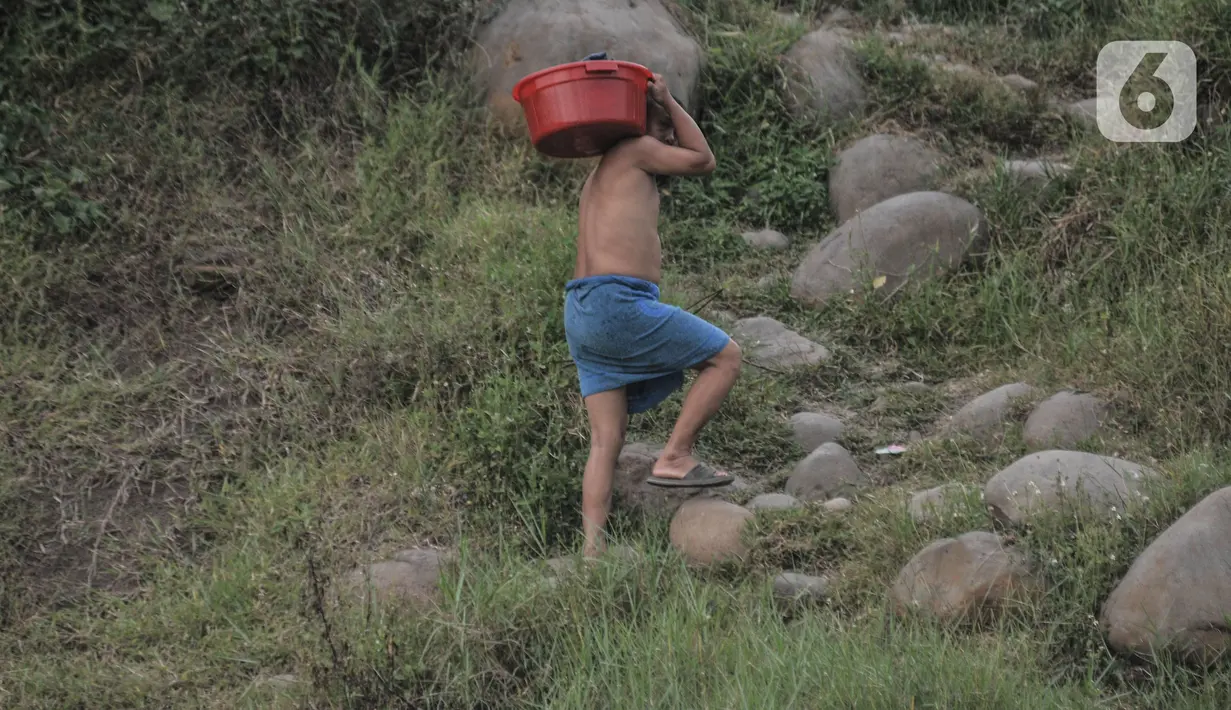 Warga membawa pakaian cucian di Sungai Cipamingkis, Jonggol, Kabupaten Bogor, Jawa Barat, Rabu (16/6/2021). Aliran Sungai Cipamingkis masih menjadi andalan warga setempat untuk kebutuhan mandi, cuci, dan kakus (MCK) lantaran ketersediaan air tanah yang terbatas. (merdeka.com/Iqbal S. Nugroho)