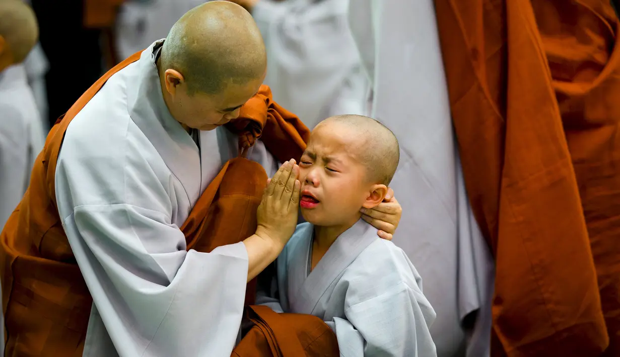 Seorang biksu Budha tampak menghibur seorang biksu pemula saat upacara pemberkatan Biksu di kuil Jogye, Seoul, Senin (11/5/2015). Sepuluh orang anak diberikan kesempatan untuk mengalami kehidupan sebagai biksu selama dua minggu. (REUTERS/Thomas Peter)
