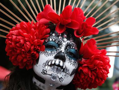 Seorang wanita berdandan ala tengkorak saat mengikuti parade Hari Orang Mati di Mexico City, Meksiko, Sabtu (26/10/2019. Para peserta dalam parade ini mengenakan kostum dan melukis wajah mirip dengan tokoh tengkorak Meksiko yang ikonik, Catrina. (AP Photo/Ginnette Riquelme)