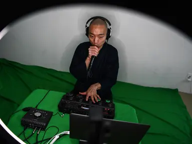 Foto yang diambil pada 26 Juni 2020 menunjukkan, Yogetsu Akasaka, seorang biksu Buddha yang juga seniman beatbox, menampilkan pertunjukan beatboxing secara live streaming di rumahnya di Tokyo. (CHARLY TRIBALLEAU/AFP)