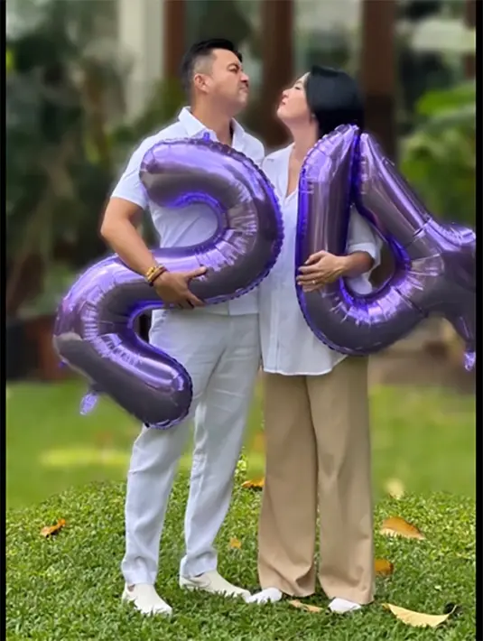 Pasangan yang telah dikaruniai dua orang anak itu memegang balon dengan angka 24. Sebagai hari anniversary pernikahannya. [Instagram/bu_deedee]