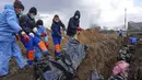 Jenazah ditempatkan pada kuburan massal di pinggiran Mariupol, Ukraina, 9 Maret 2022. Warga tidak dapat menguburkan orang mati di antara mereka karena serangan berat oleh pasukan Rusia. (AP Photo/Evgeniy Maloletka)