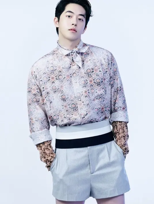 Gaya swag Nam Joo Hyuk mengenakan outfit all Dior. Kemeja printed dipadu scarf serasi yang diikatkan di lehernya, manset lengan yang lebih panjang dari lengan kemeja yang digulungnya, dikombinasikan dengan celana pendek beraksen high-waisted berwarna abu-abu. [Foto: Instagram/skawngur]